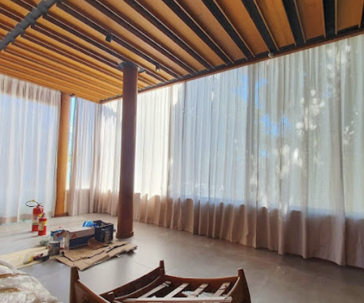 Cortinas em ambiente de pé direito alto com vigas de madeira